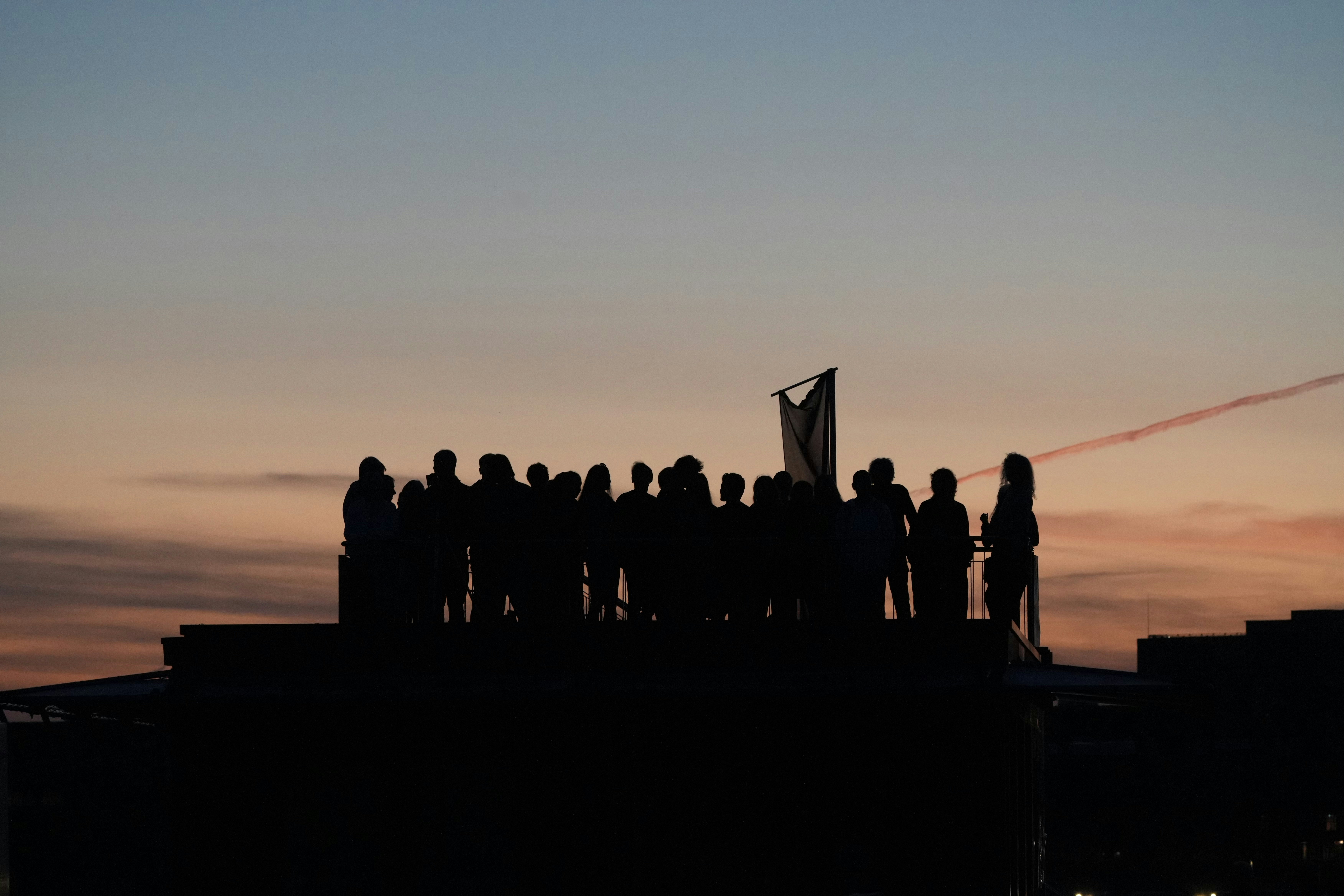 色とりどりの夕日の空を背景に屋上の群衆のシルエット
