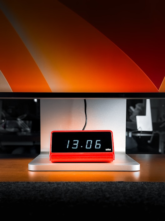 Red digital clock displaying 13:06 on a stand.