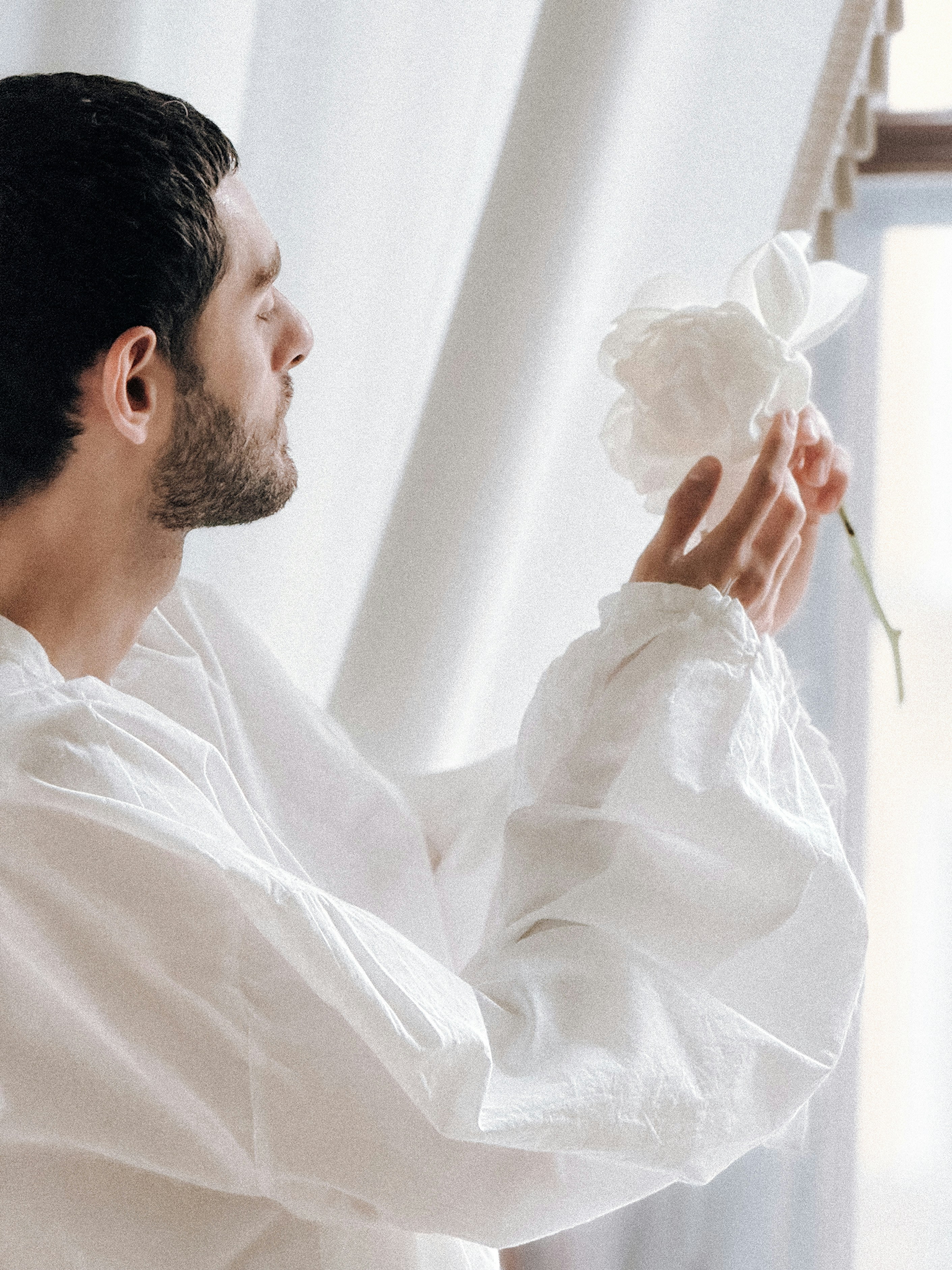 白い花を持った白いシャツの男