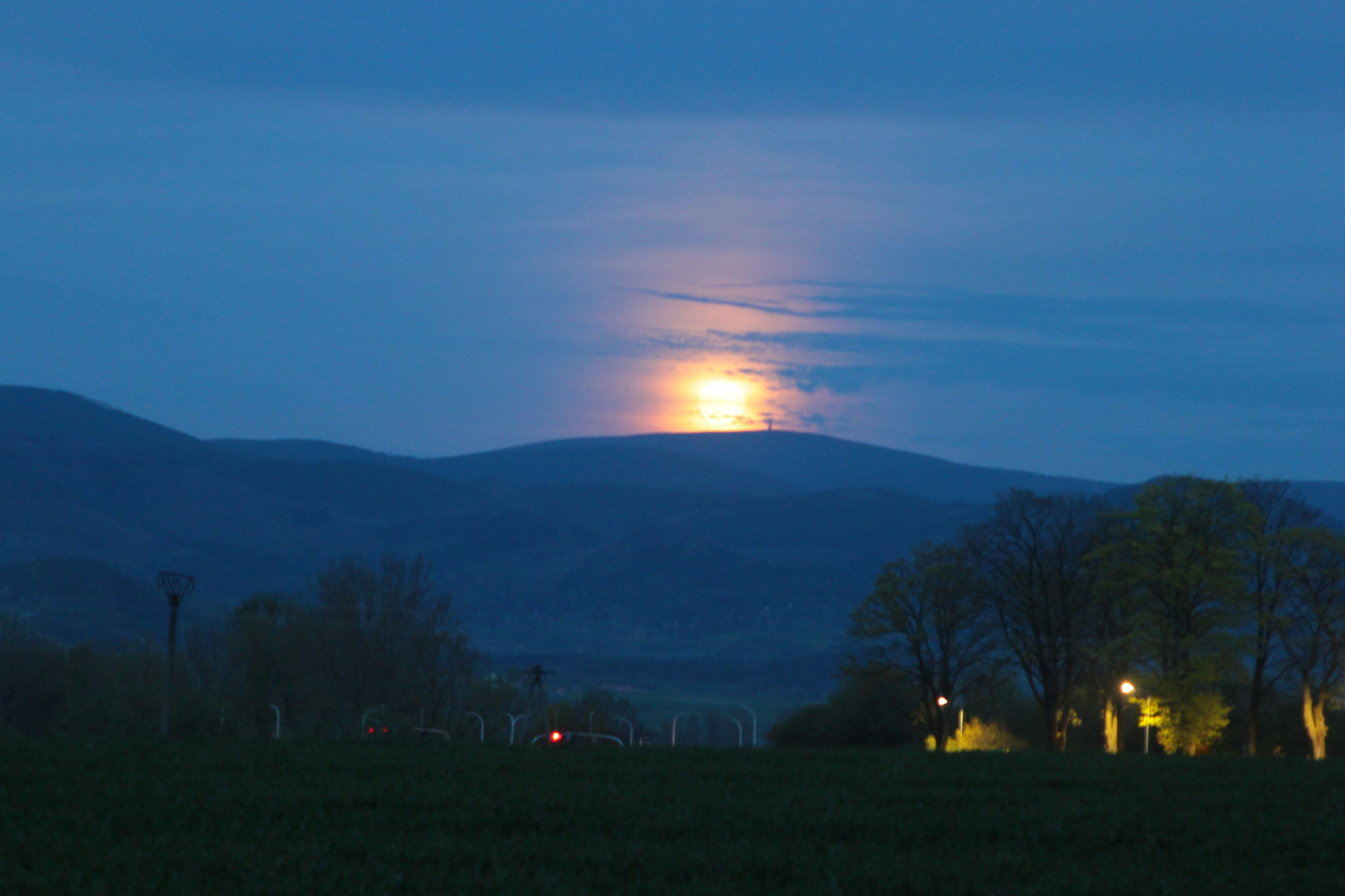 Full moon rising over rolling hills at dusk
