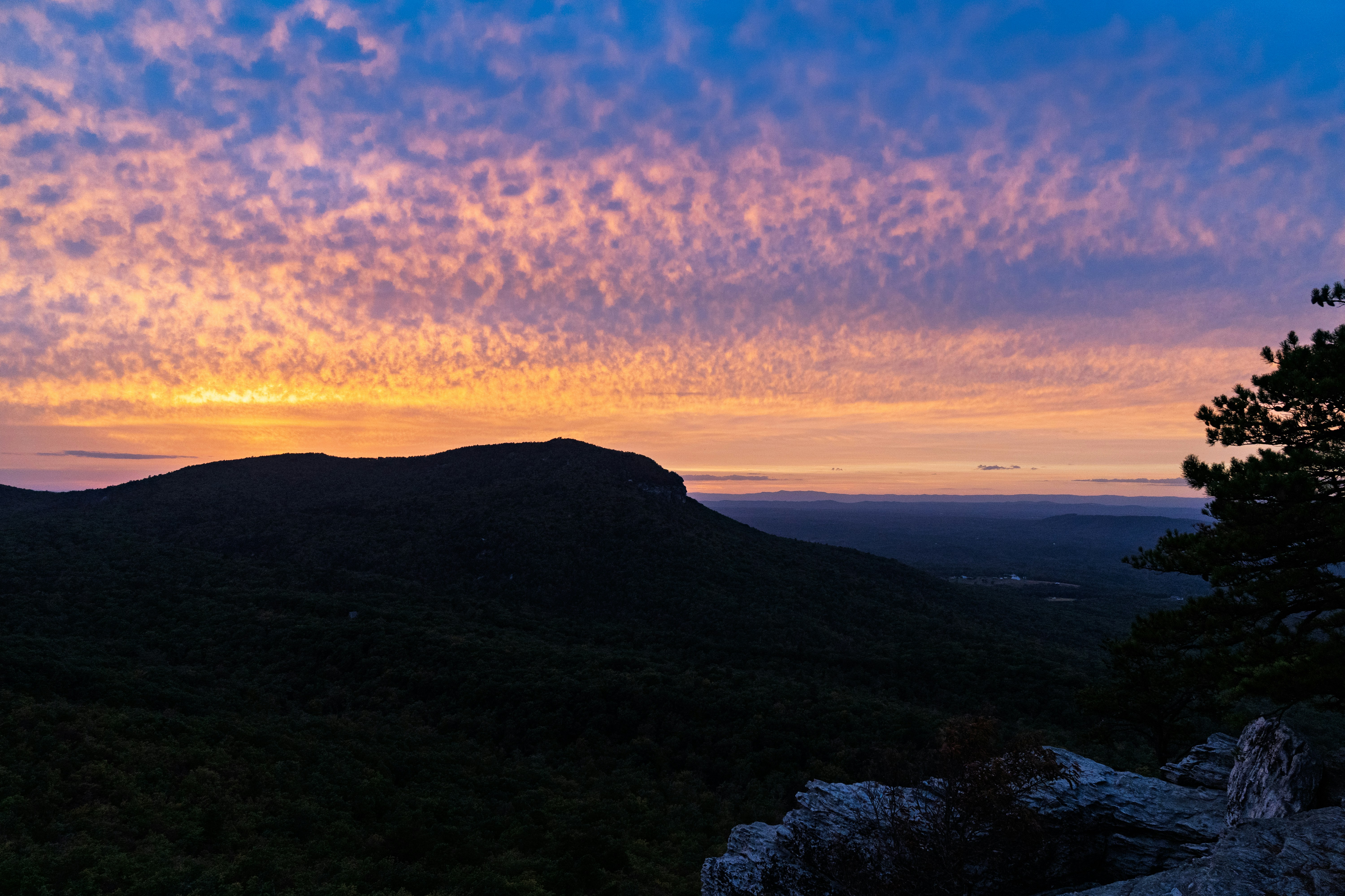 Dramatic sunset sky over a dark mountain landscape.