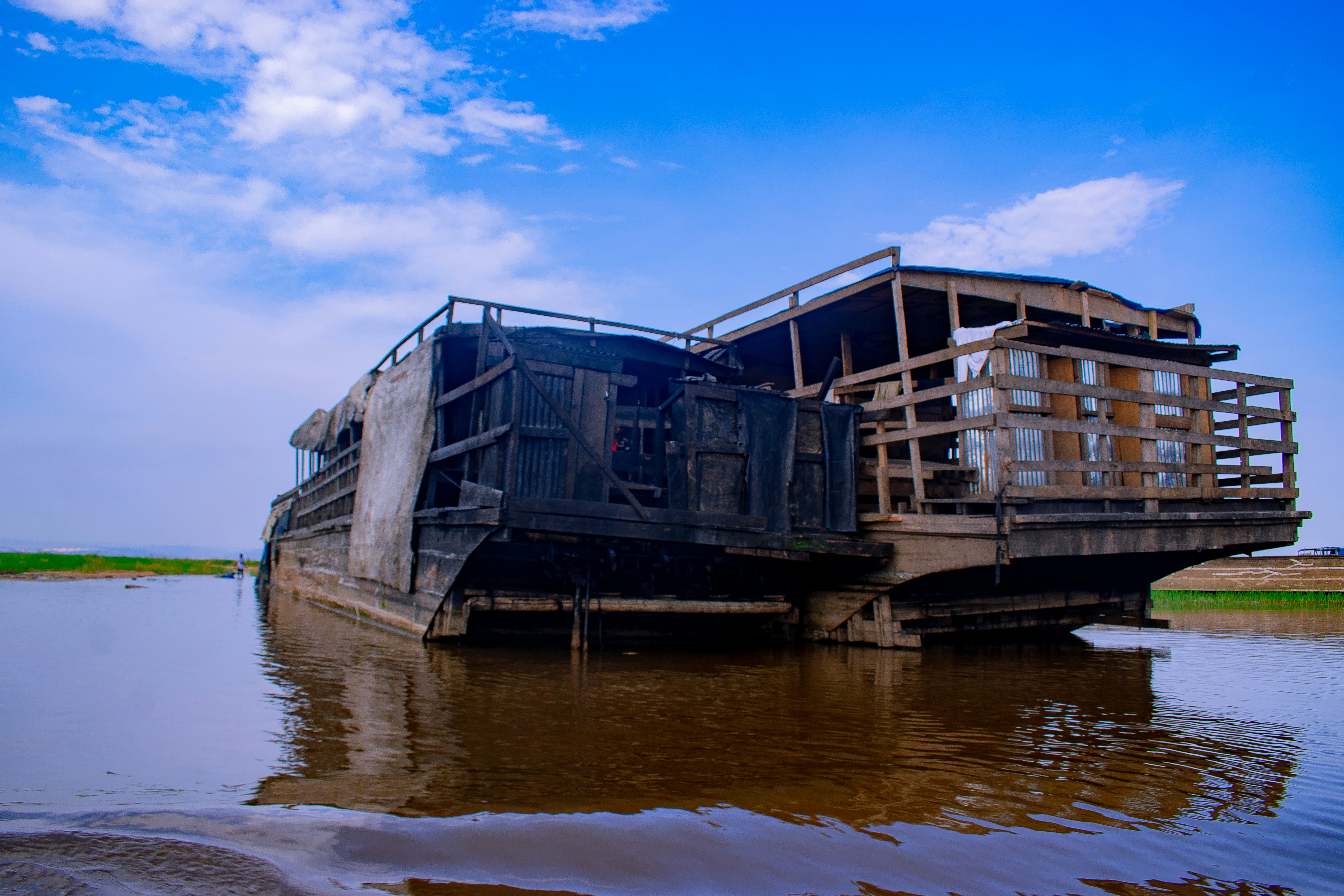 Abandoned shipwrecks rest in shallow water under a blue sky.