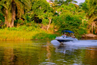 A boat cruises down a wide, calm river.