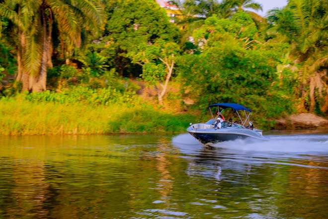 A boat cruises down a wide, calm river.