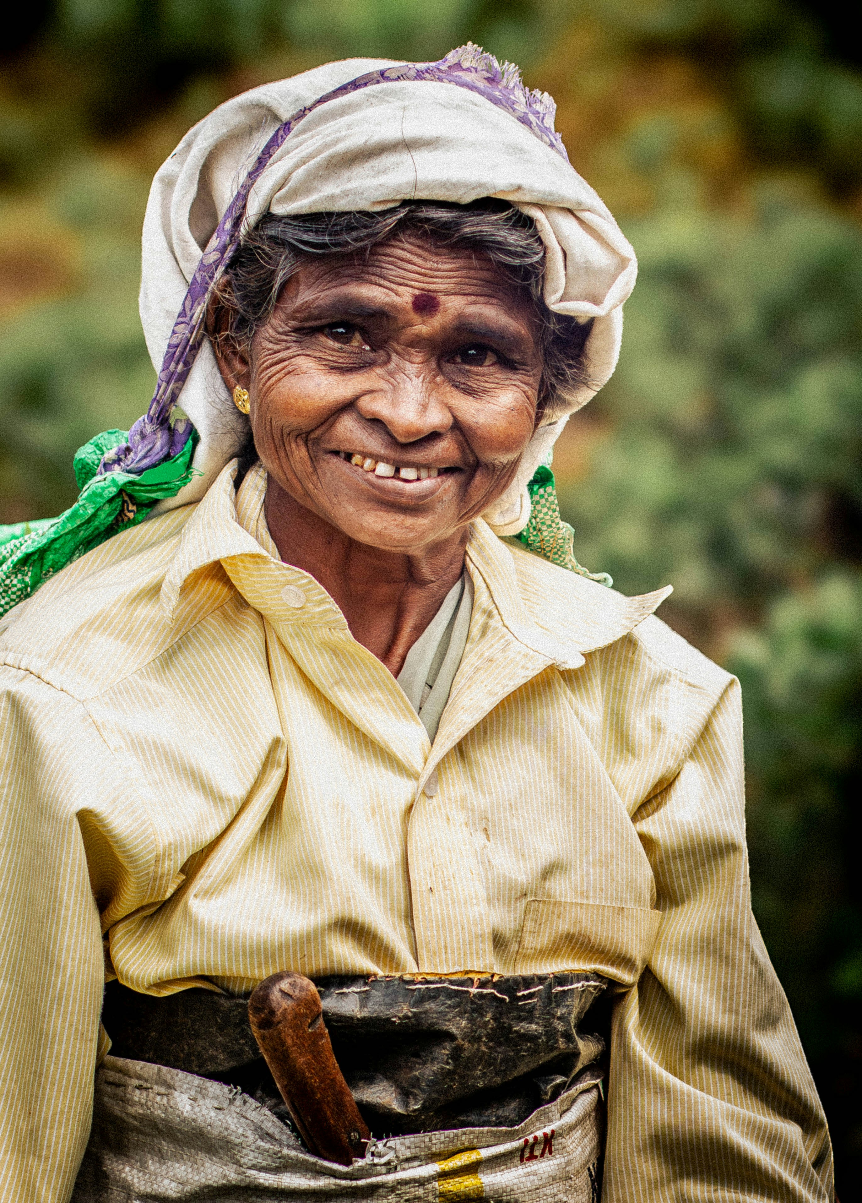 Smiling elderly woman with a headscarf and traditional clothing.