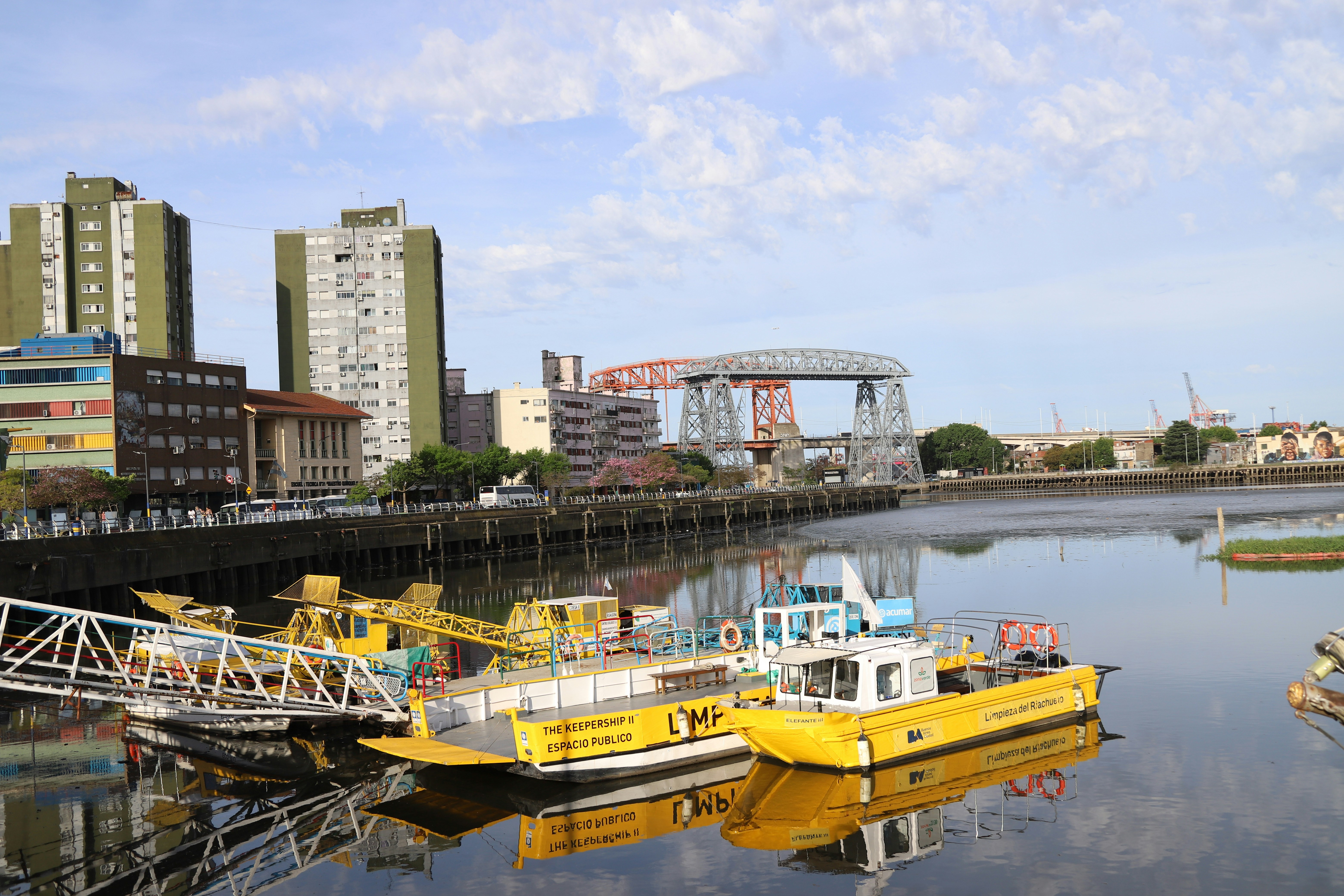 Boats docked in a city harbor with buildings behind.