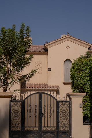 A large house with ornate gates and green trees