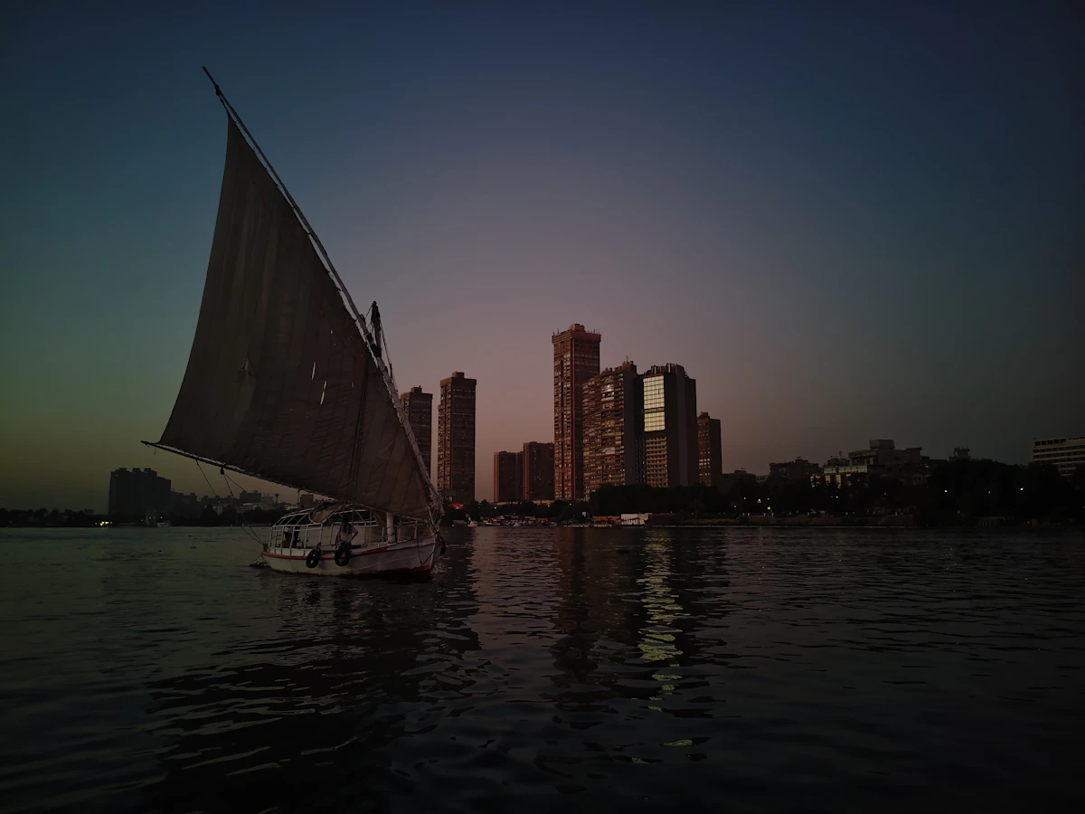 Traditional sailboat on the Nile with the Luxor skyline at dusk