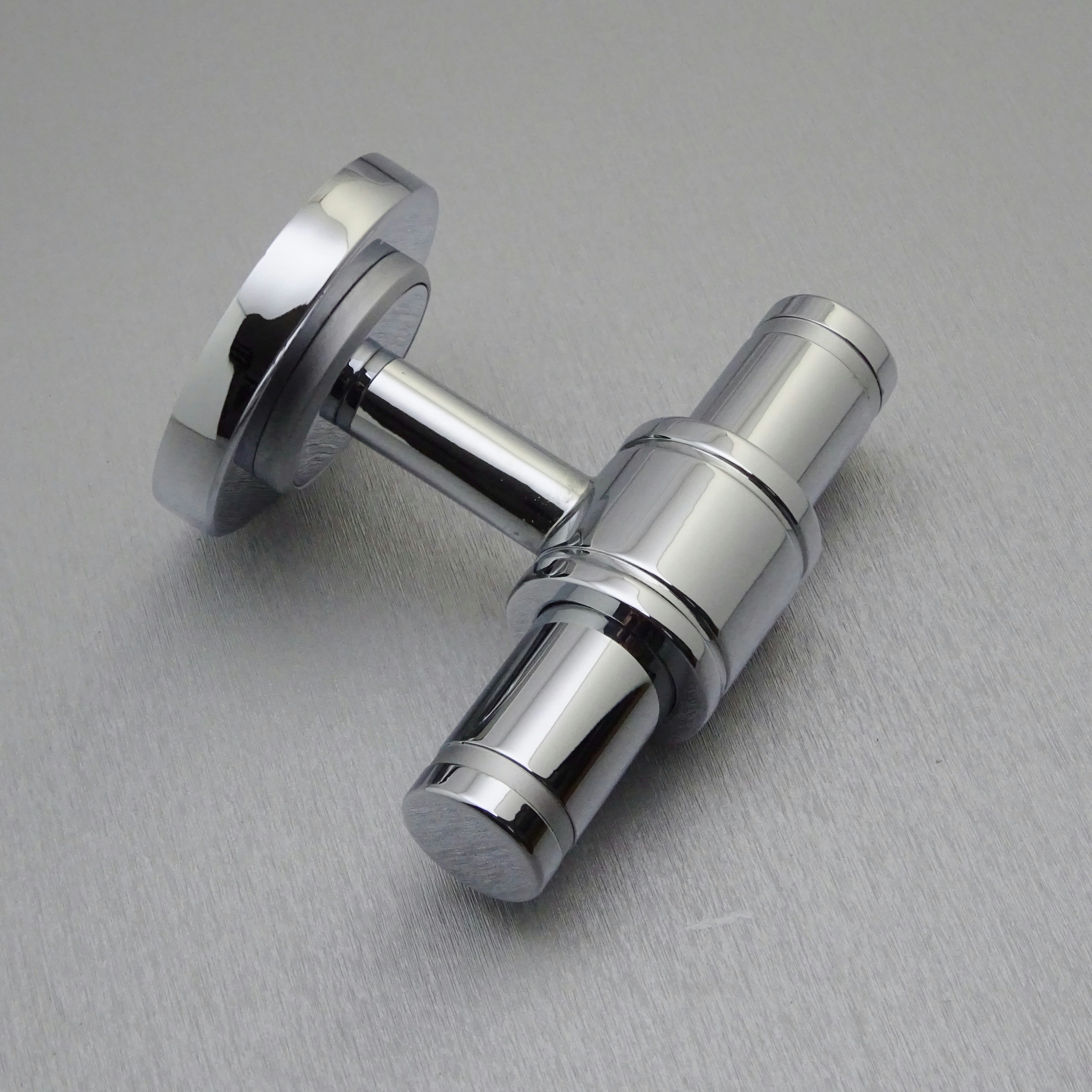 A shiny silver cufflink on a gray surface.