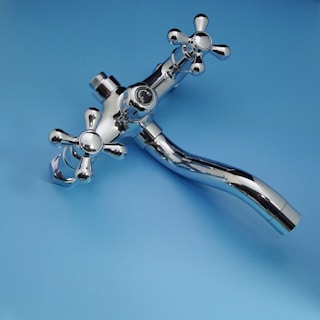 Chrome faucet with cross handles on blue background