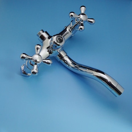 Chrome faucet with cross handles on blue background