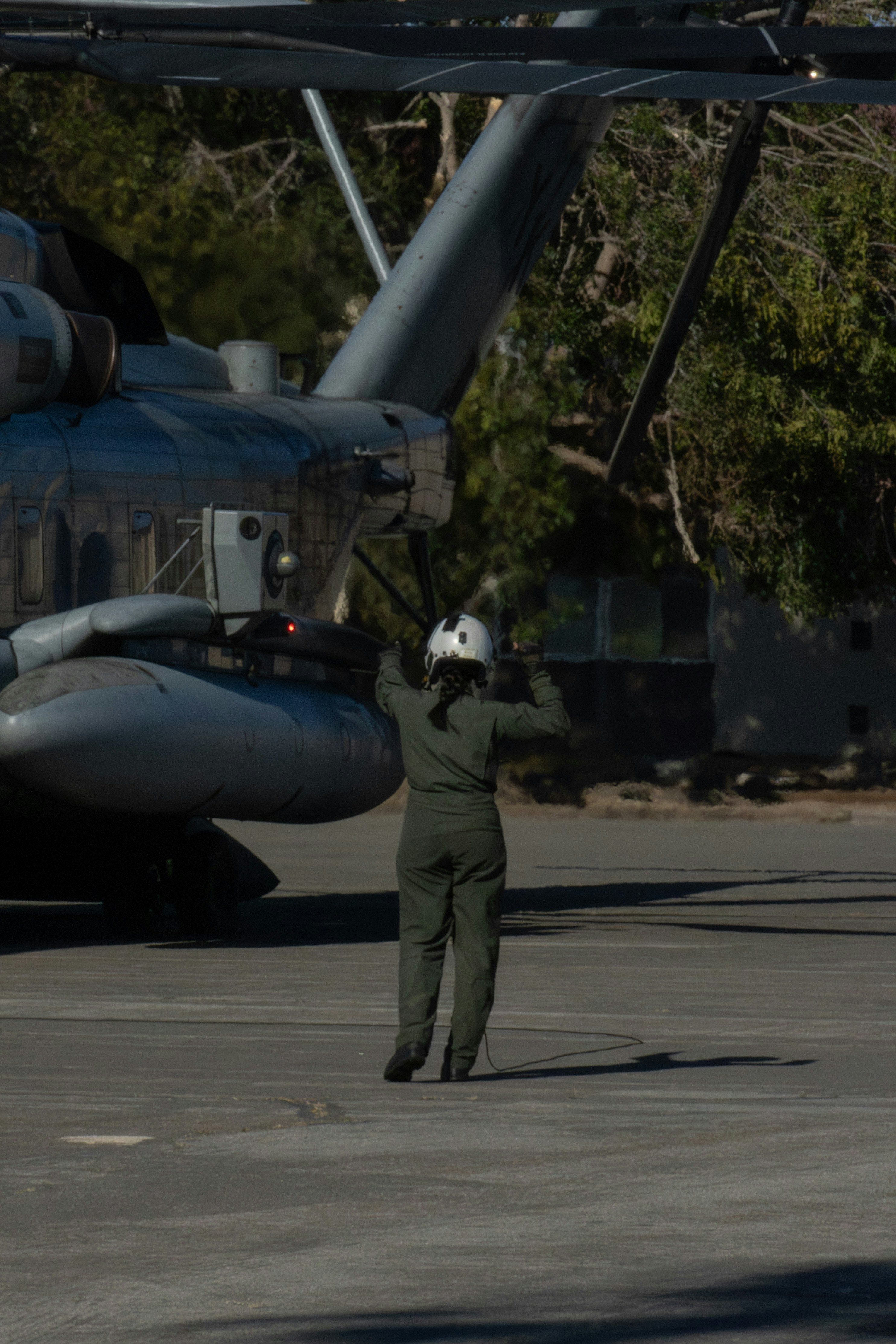 Person in uniform directing a large aircraft on tarmac.