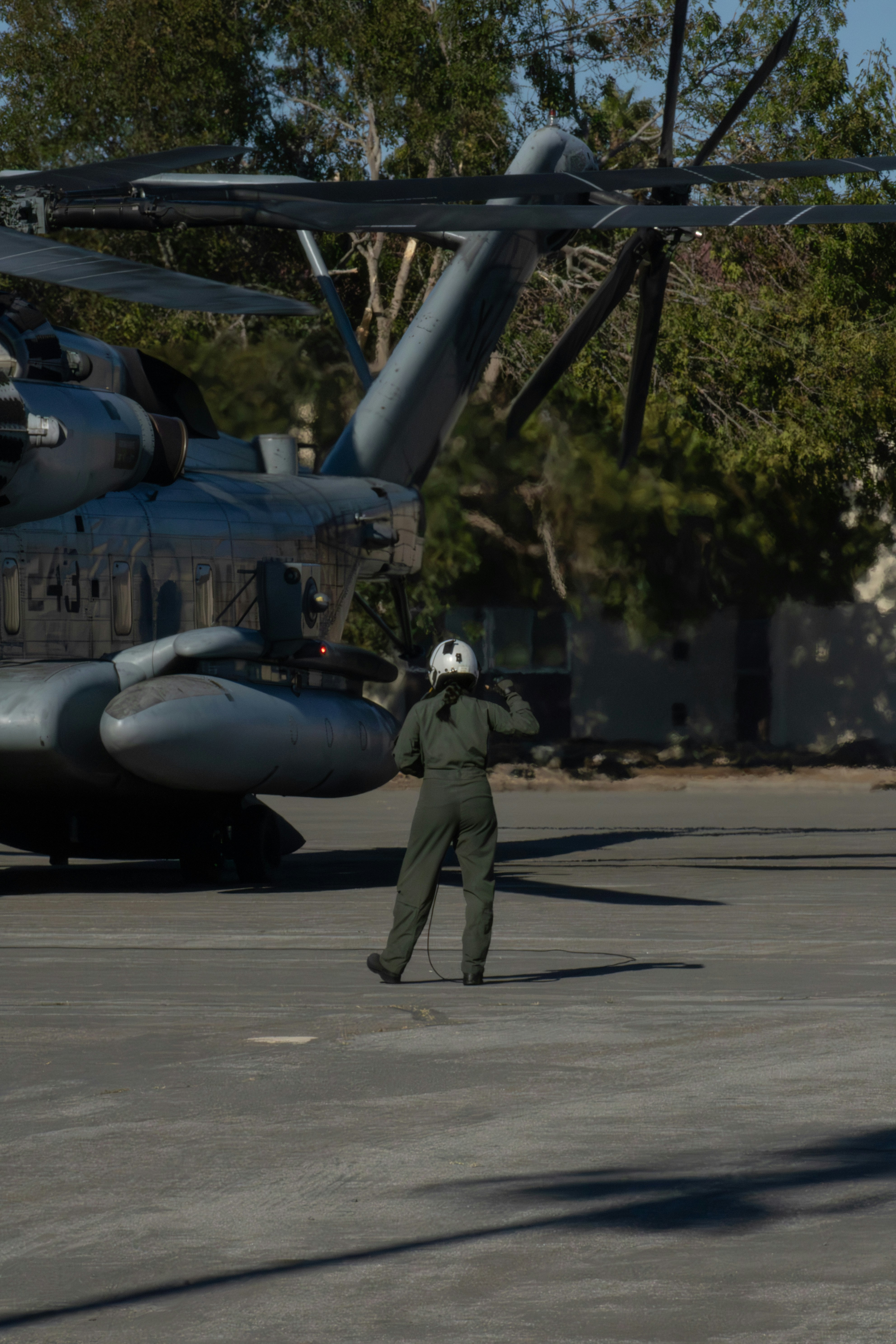 Pilot standing by large helicopter on tarmac