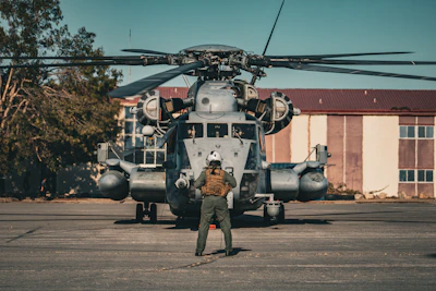 Pilot stands before a large military helicopter on tarmac