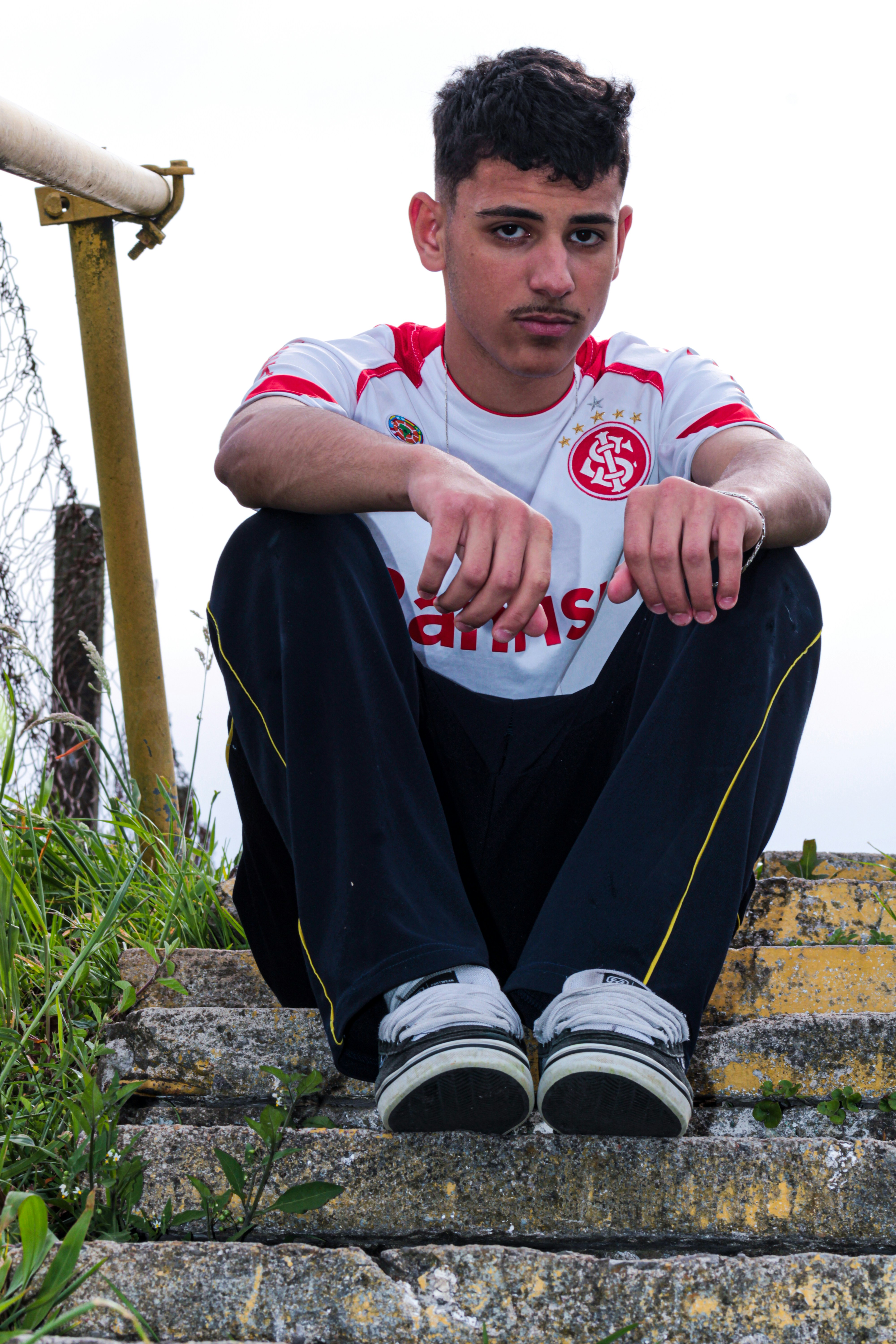 Young man in soccer jersey sitting on stadium stairs