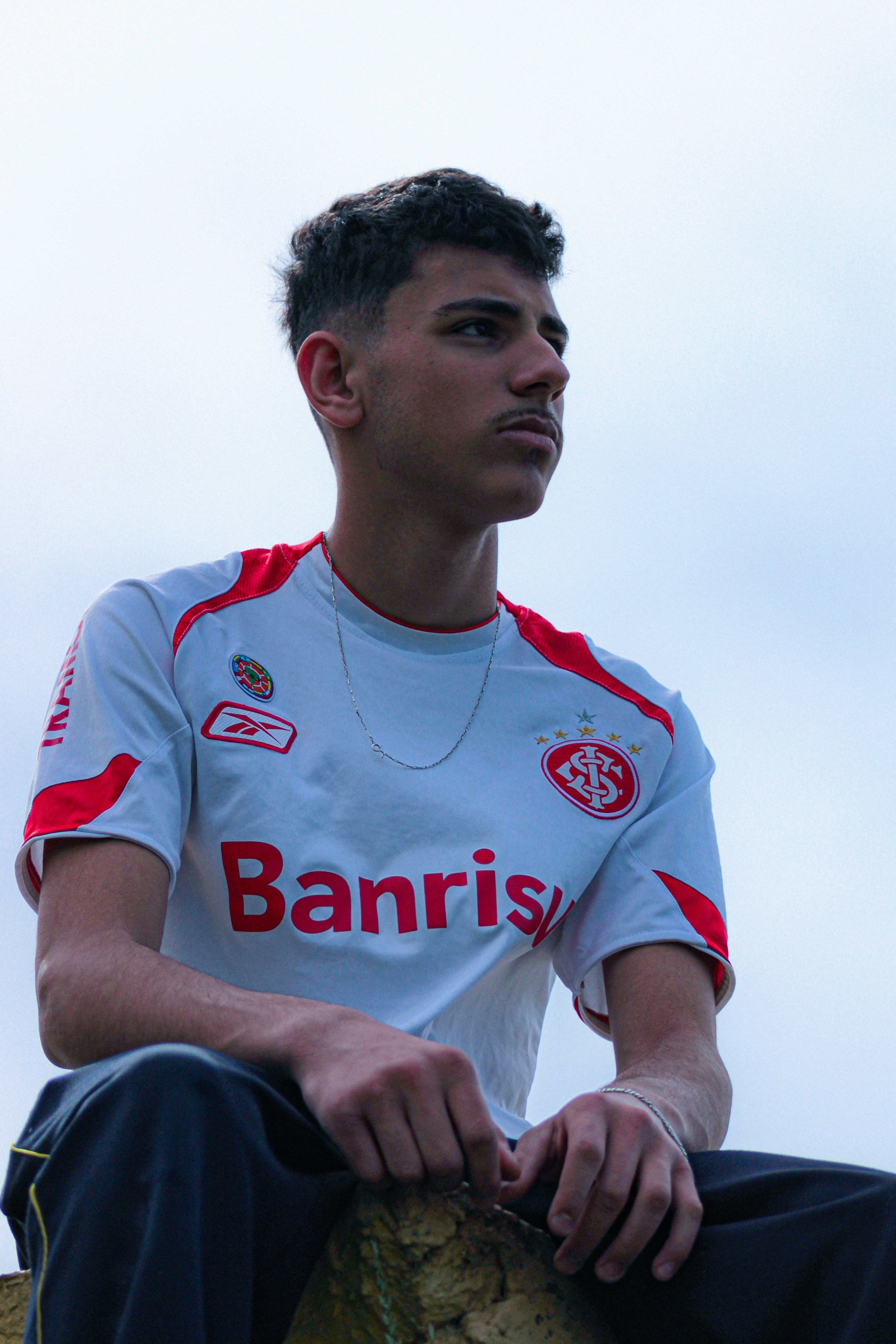Jeune homme en maillot de football blanc regardant ailleurs