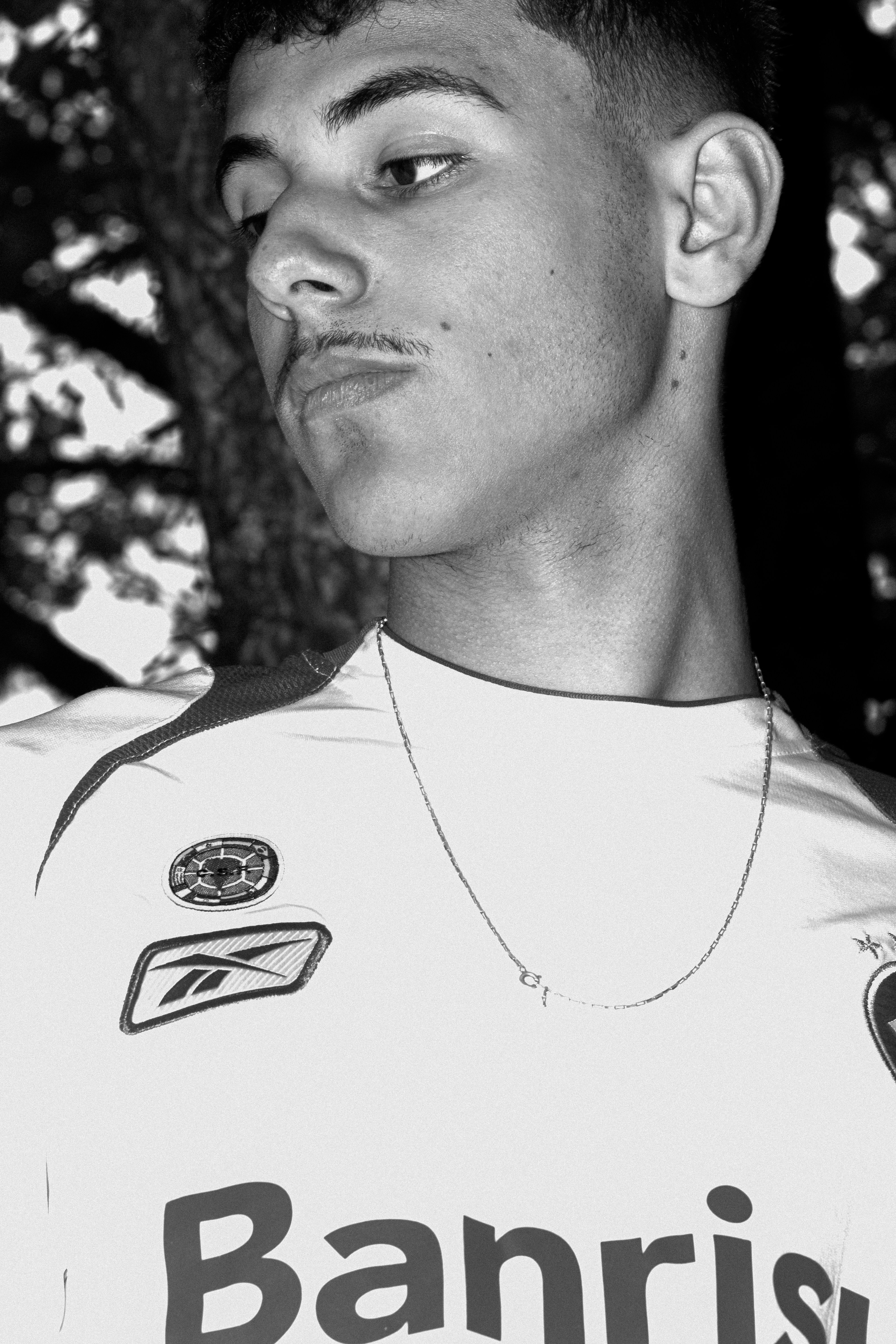 Young man wearing a white jersey with logos.