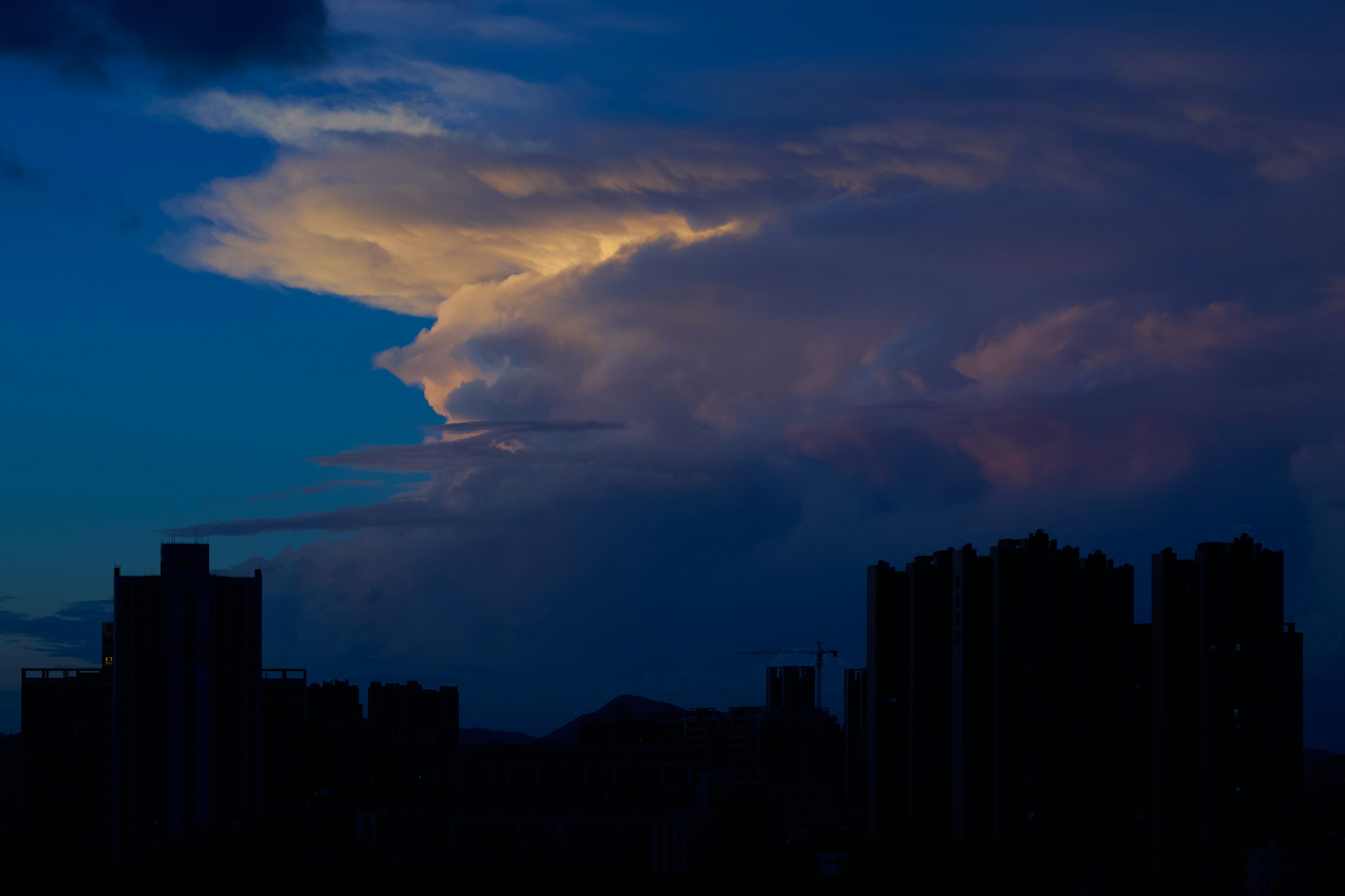 Dramatic clouds over silhouetted buildings at dusk