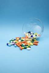 Various colorful pills spilled from a glass bowl.