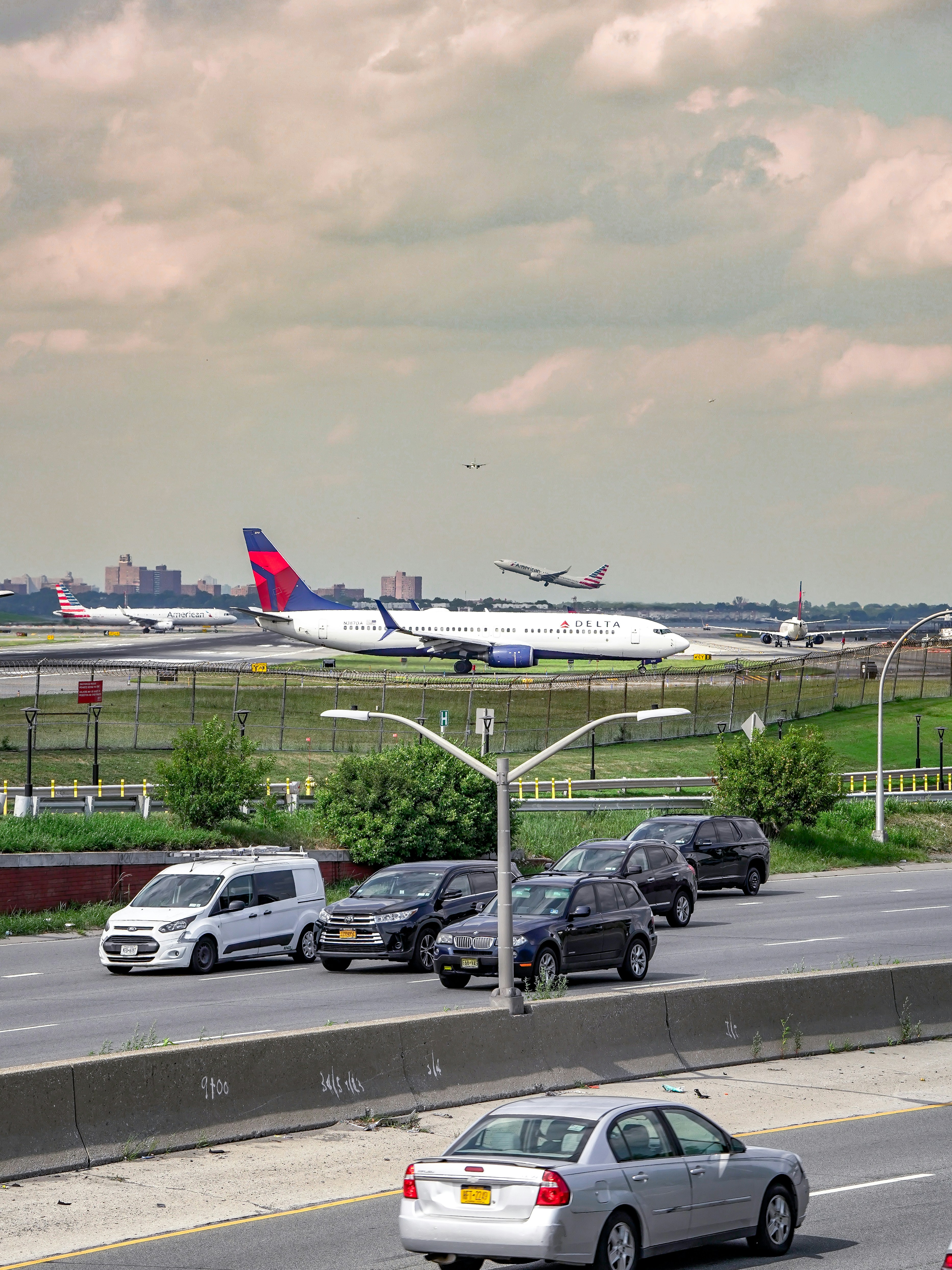 Airplane on runway with cars on highway.
