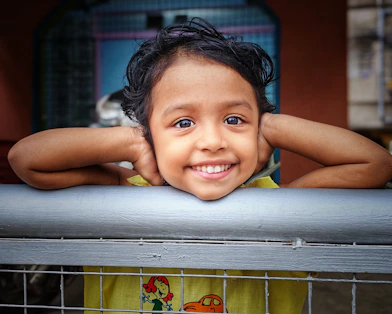 A smiling young child with dark curly hair.