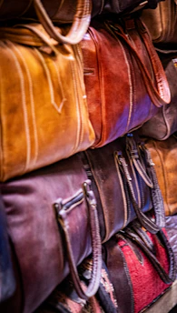 Stack of colorful leather bags in a market.