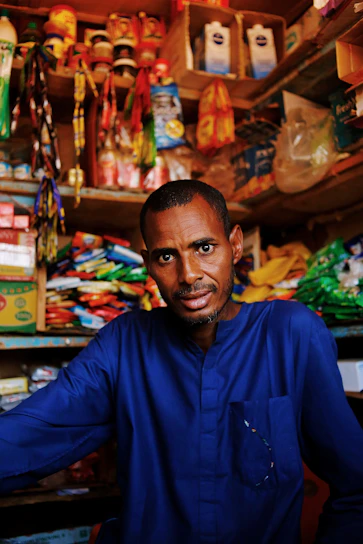 Man in blue shirt standing in a small shop.