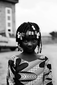 Young girl with braided hair and beads looks forward.
