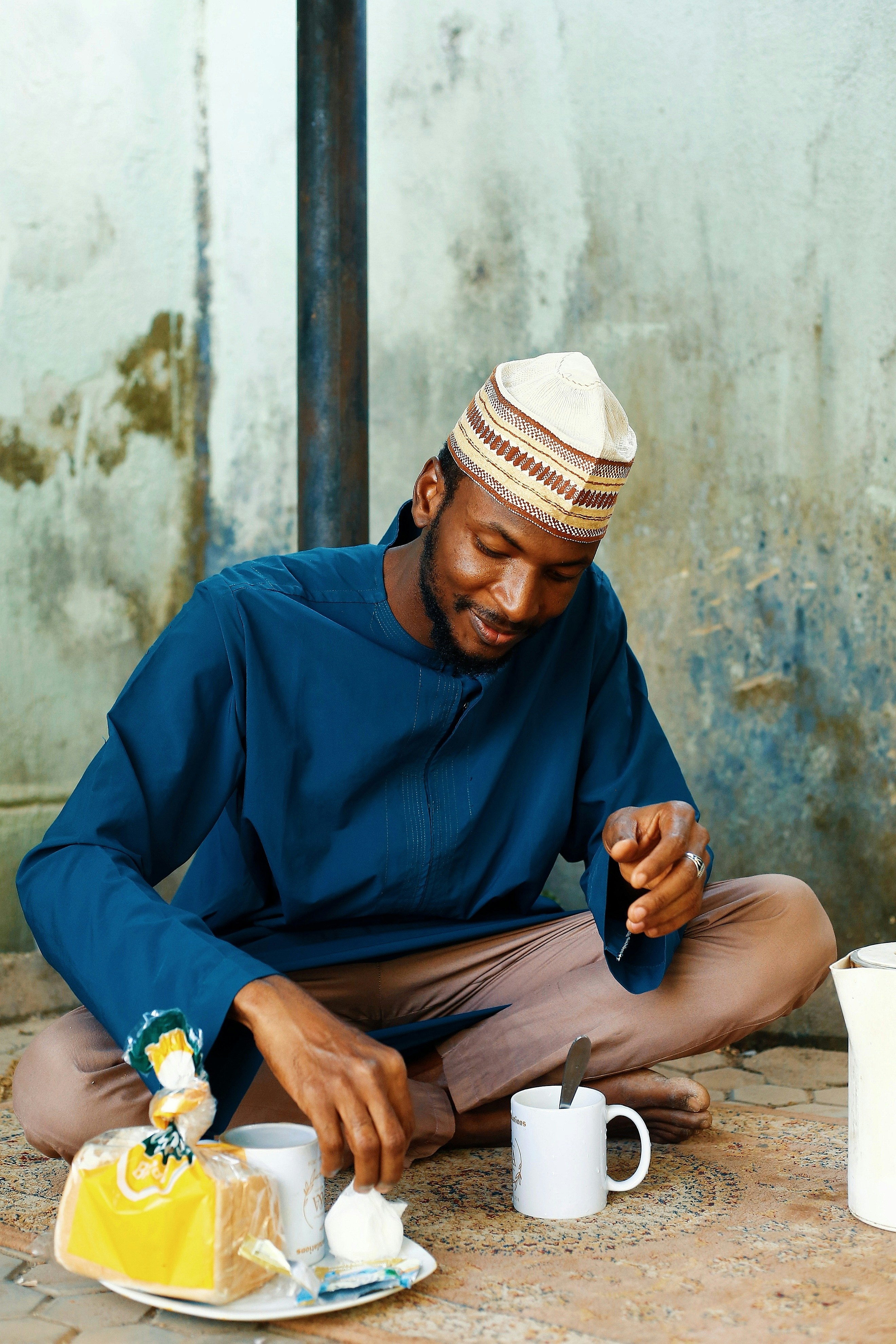 Man in traditional clothing eating bread and drinking tea.