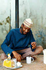Man in traditional clothing eating bread and drinking tea.