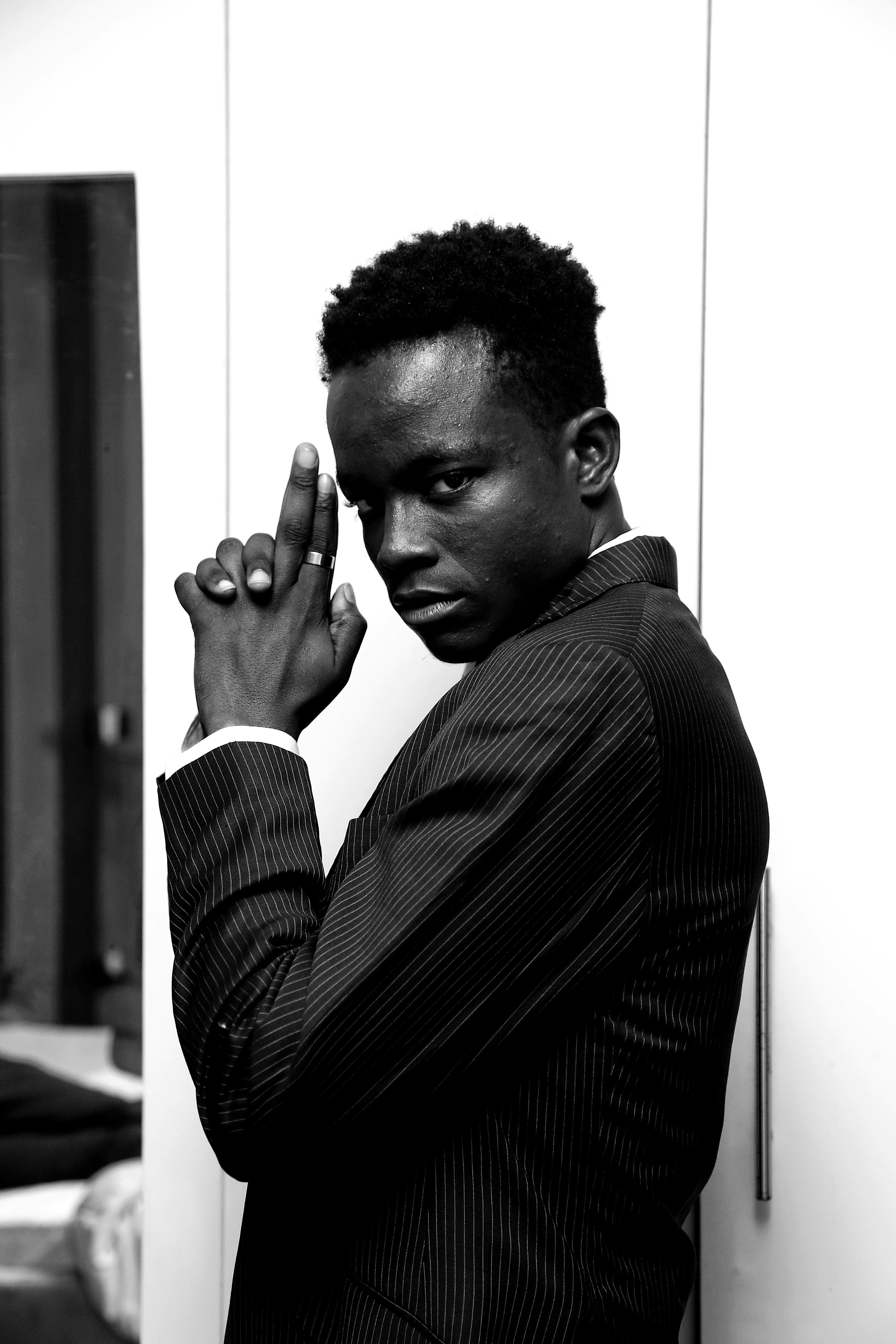 Man in suit points finger gun towards camera