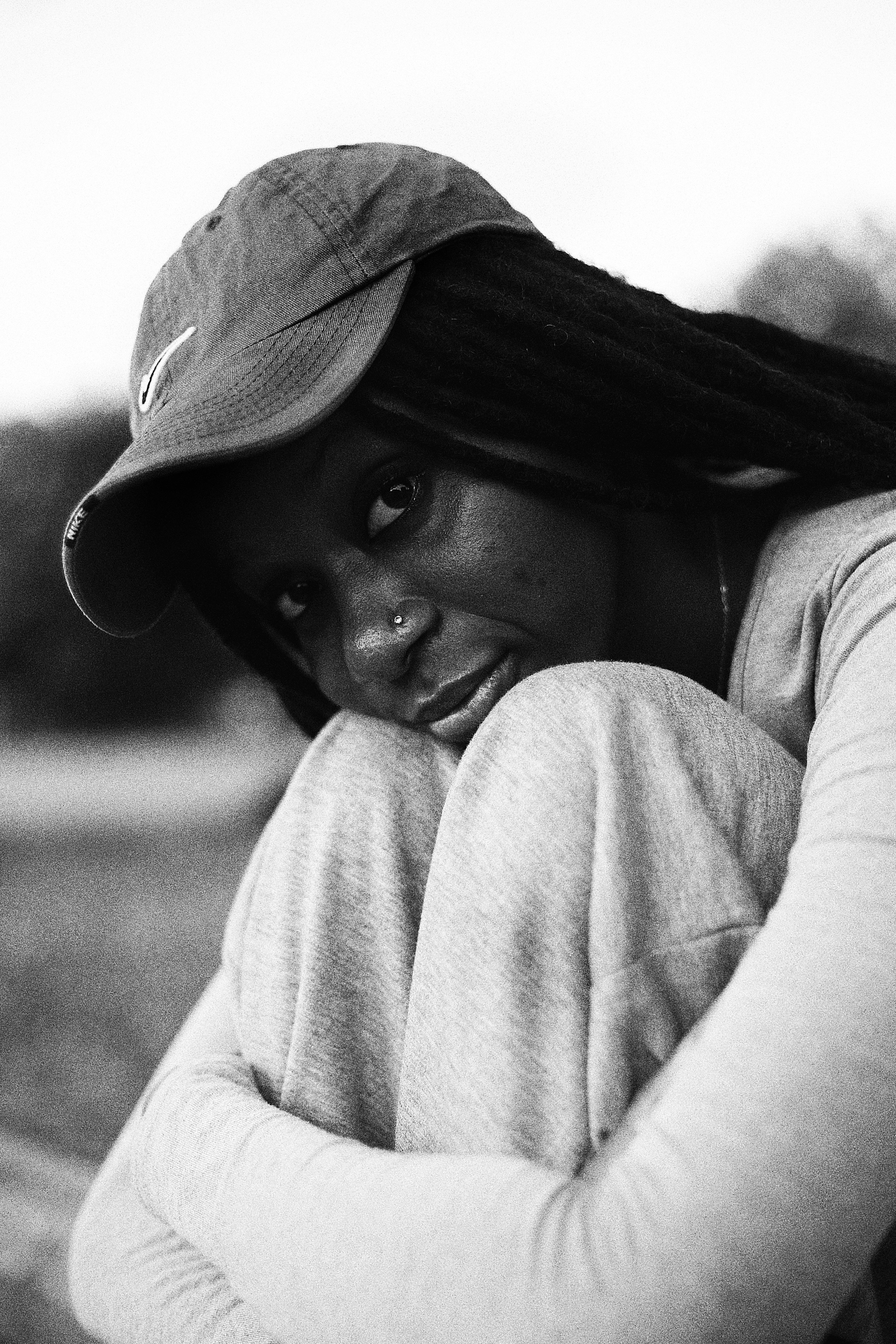 A woman wearing a baseball cap and dreadlocks.