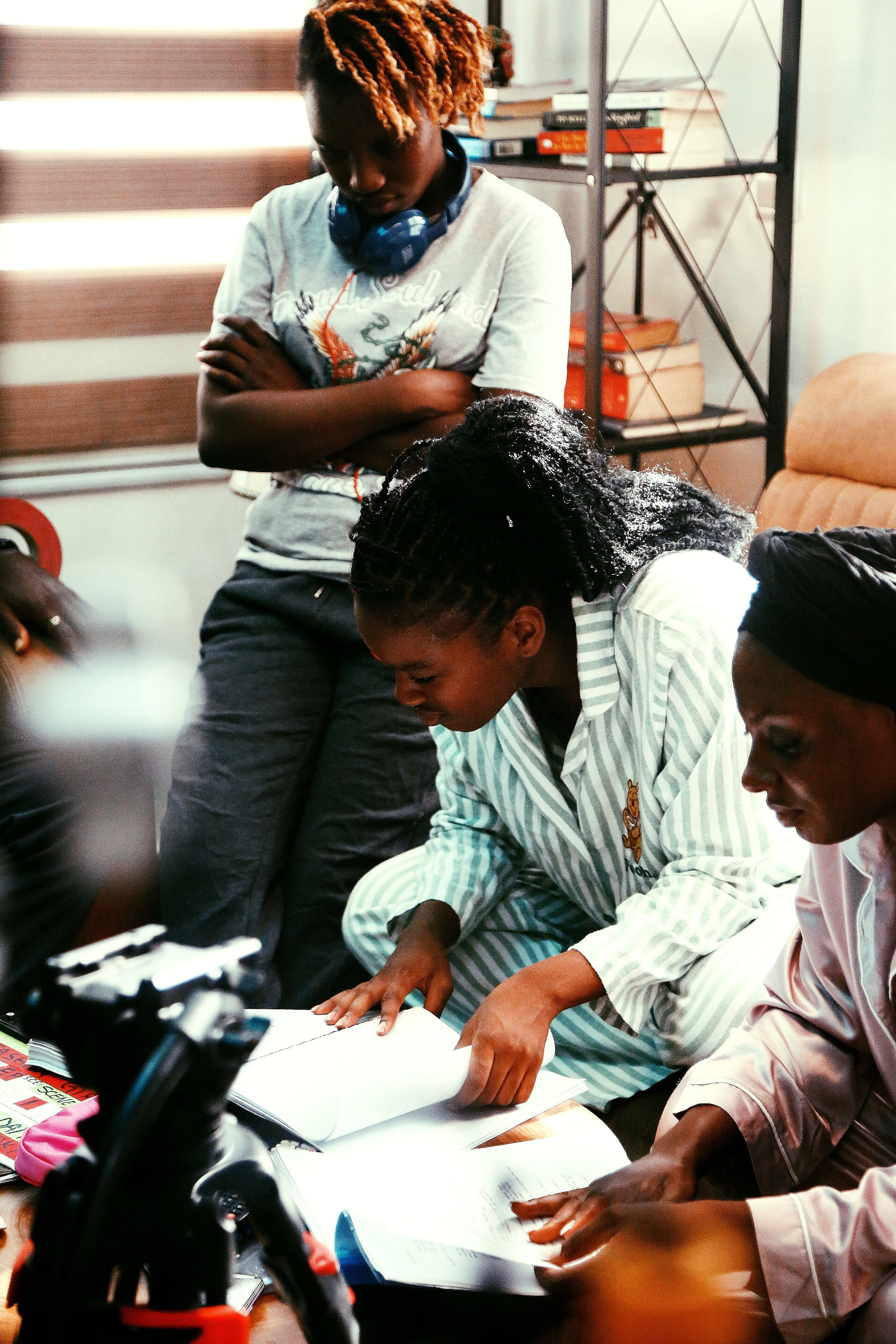 Three women leaning over a table indoors, reading through papers together