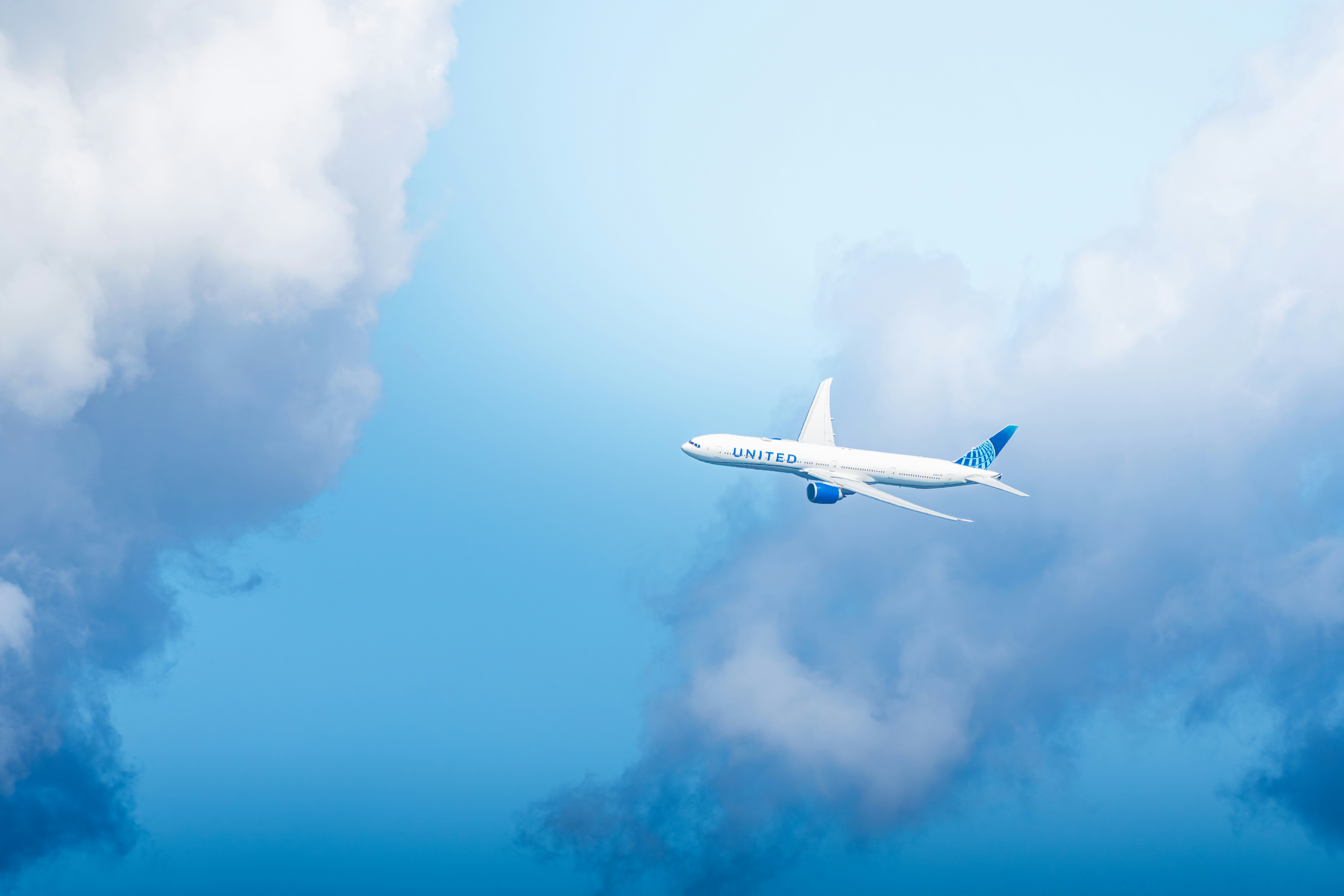 Un avión blanco volando a través del cielo azul nublado.