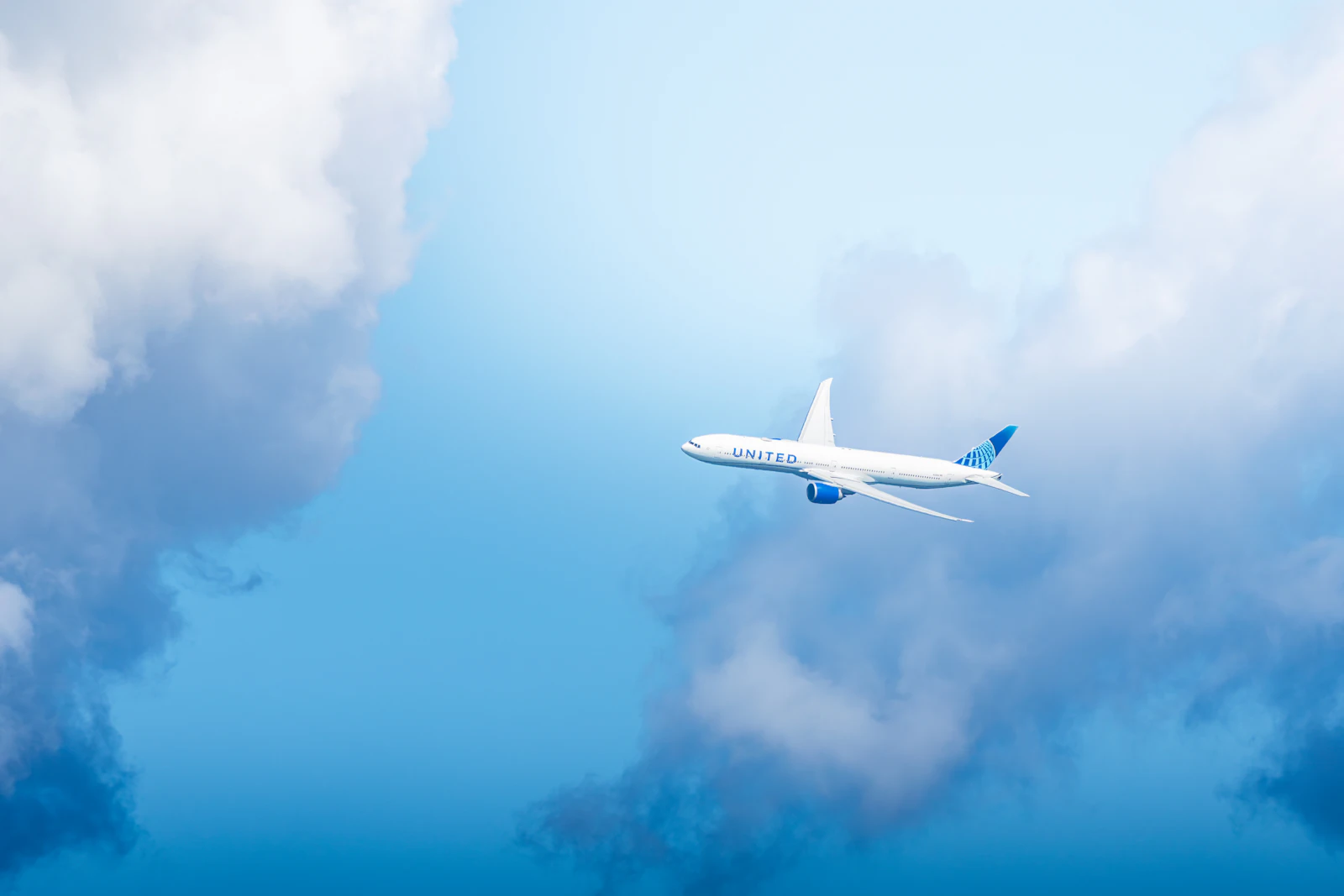 White airliner flying through a bright blue sky