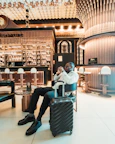 Man sitting with suitcase in stylish hotel lobby.