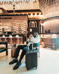 Man sitting with suitcase in stylish hotel lobby.