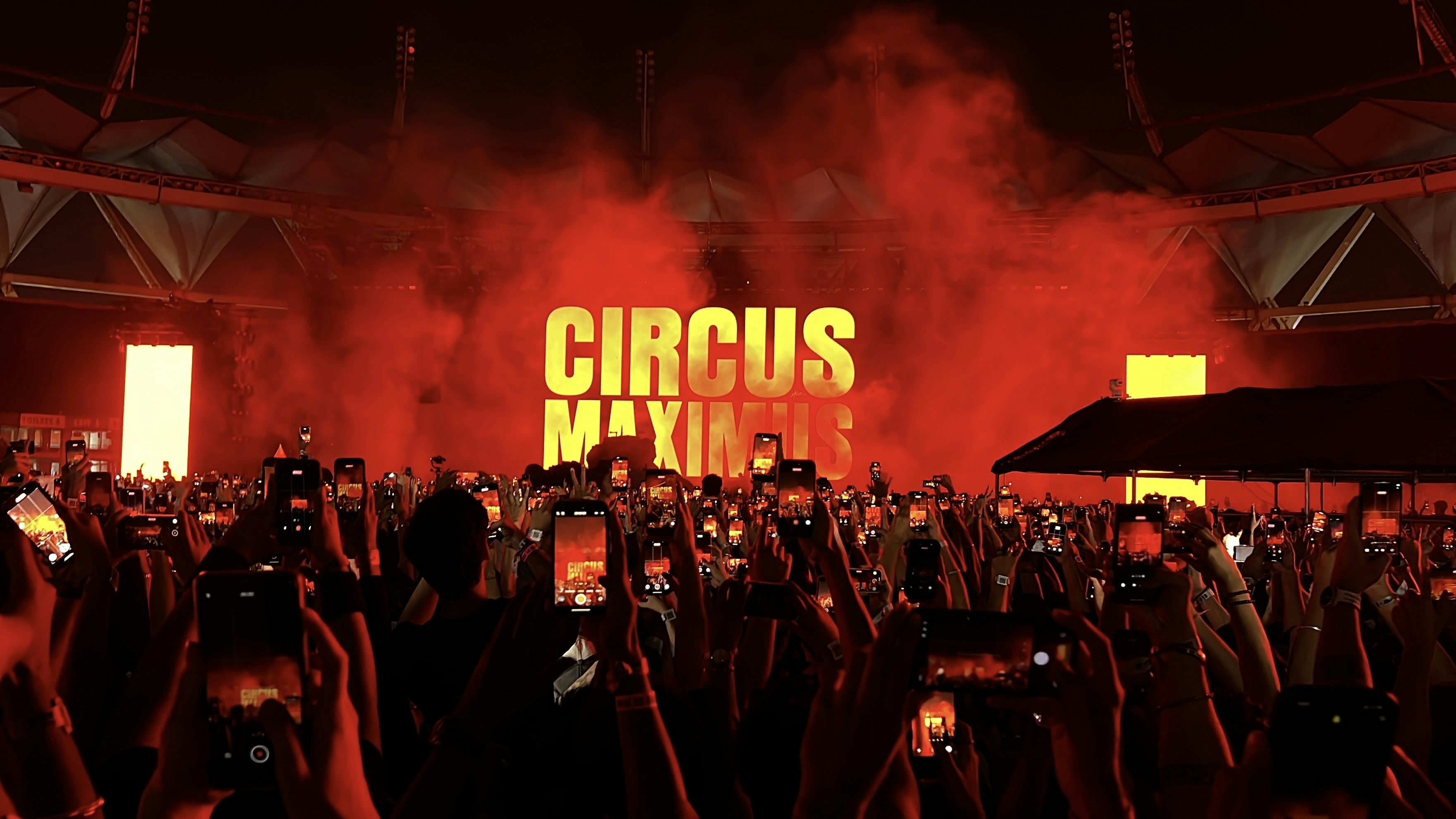 Crowd watches a concert with "circus maximus" sign.