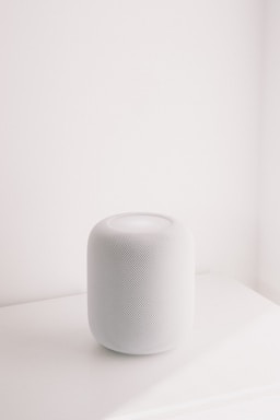 A white smart speaker on a white surface.