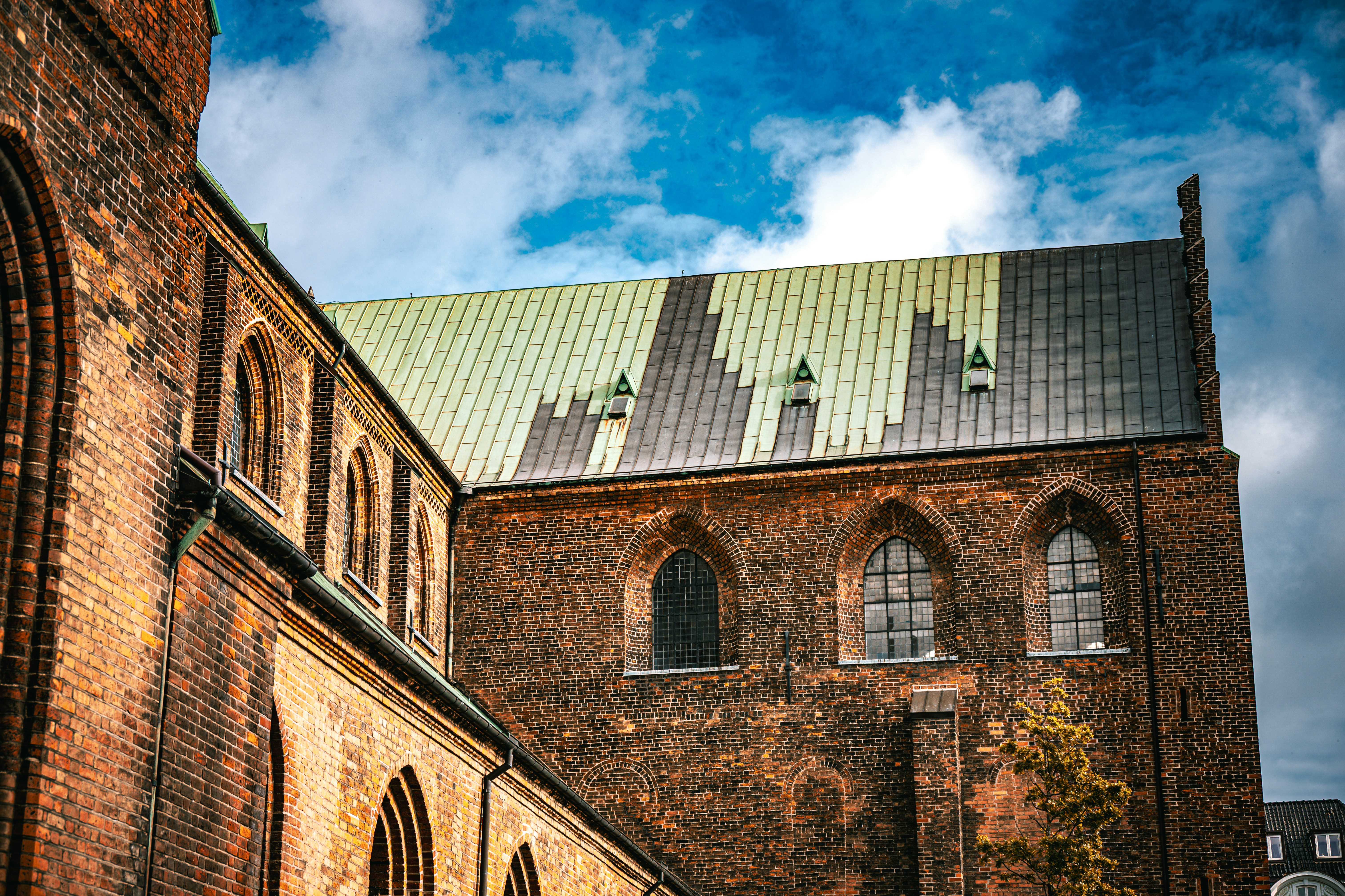 Brick cathedral with arched windows and green roof.