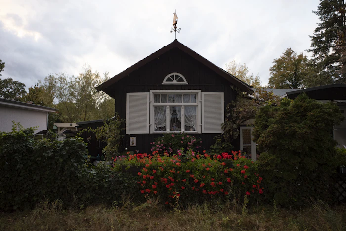 Dark wooden house with white shutters and flowers