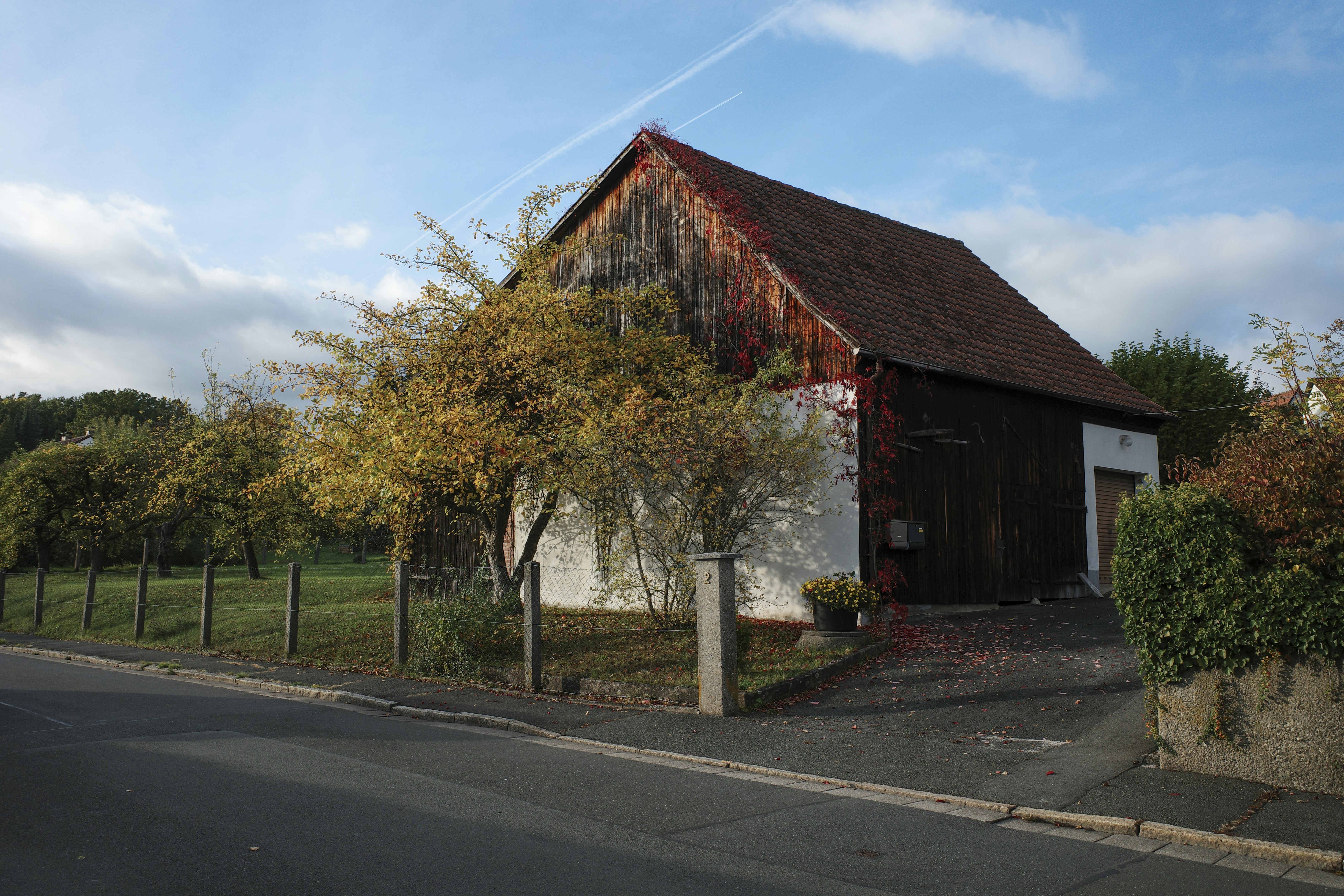 Old wooden barn with autumn trees and blue sky