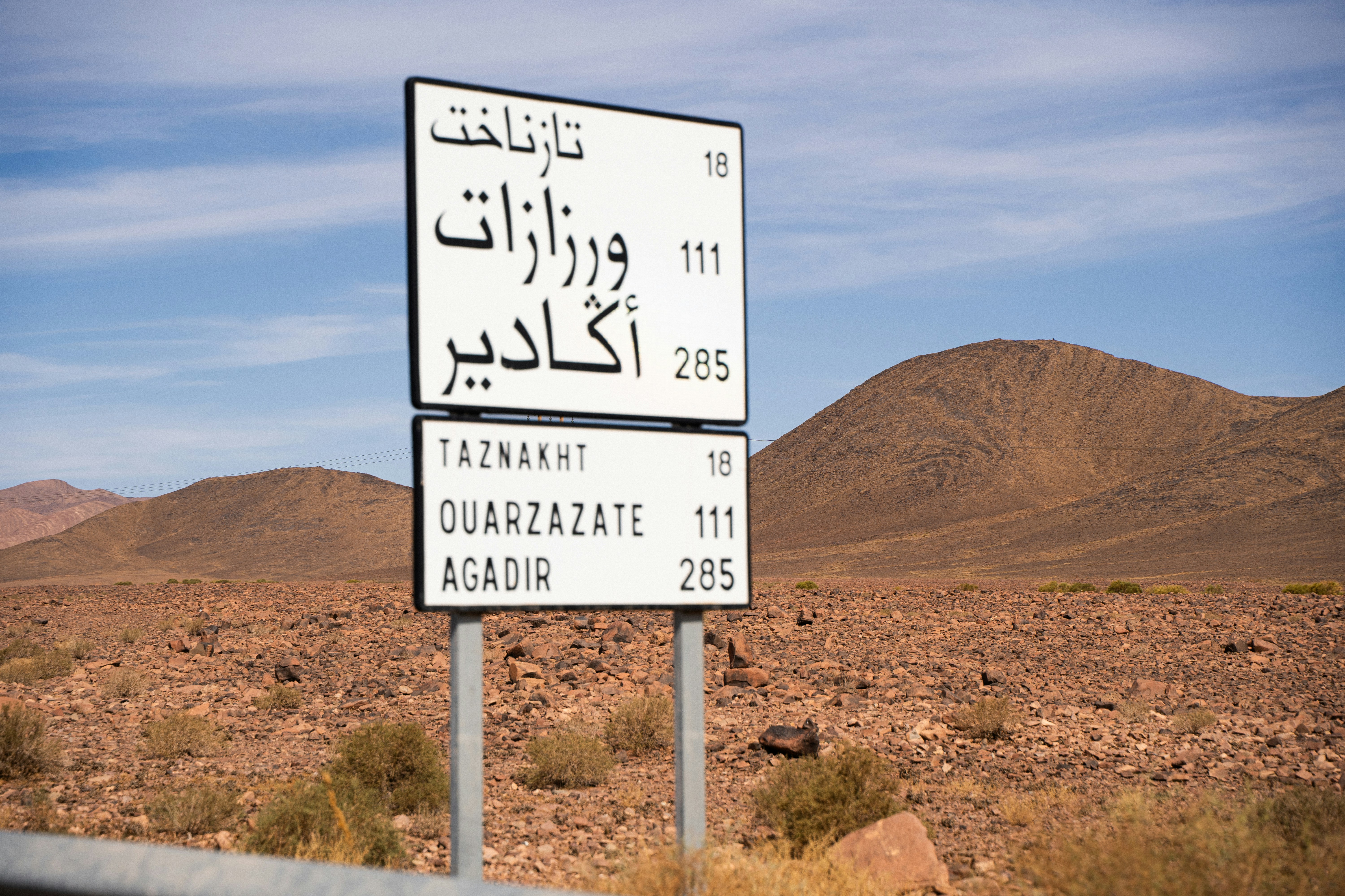 Road sign in a desert landscape with mountains.