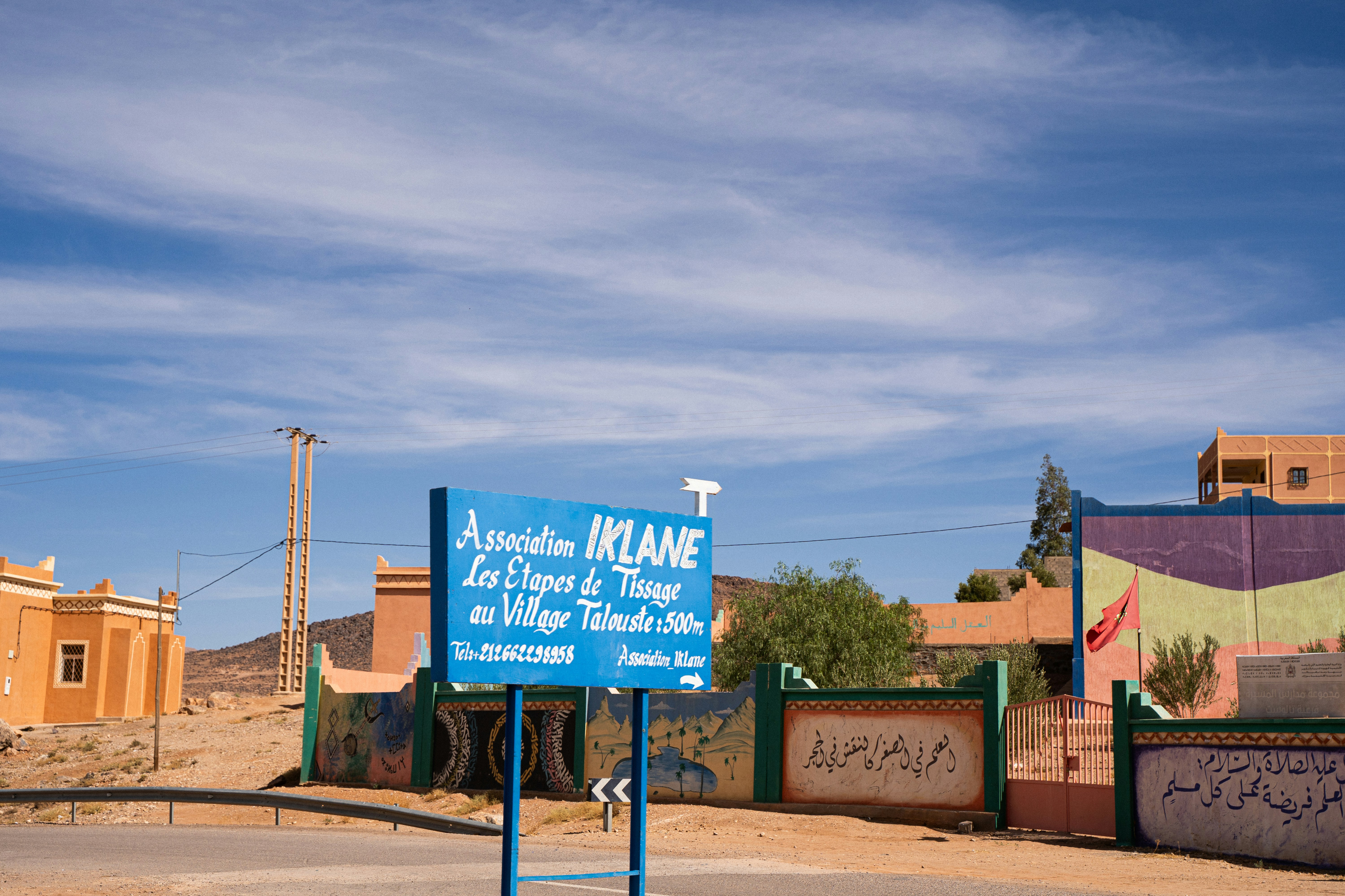 Blue sign in front of colorful buildings under sky