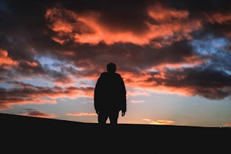 Silhouette of a person against a dramatic sunset sky.