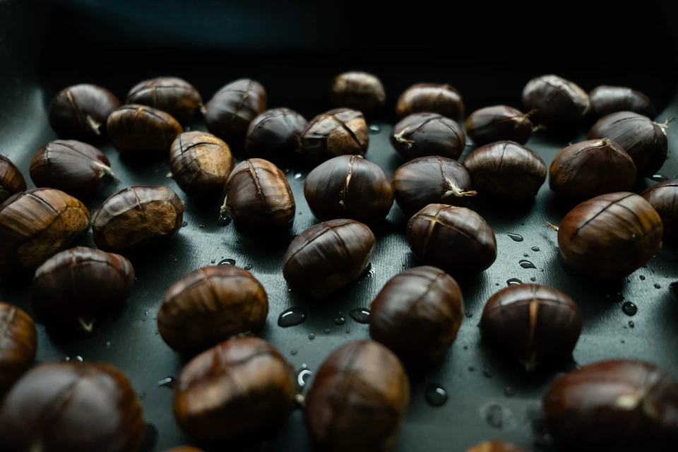 Roasted chestnuts glistening on a dark tray at a São Martinho street stall