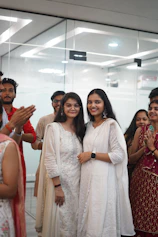 Two women in white smiling with people clapping