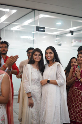 Two women in white smiling with people clapping