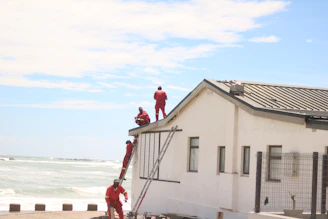 Workers in red suits on a white building roof