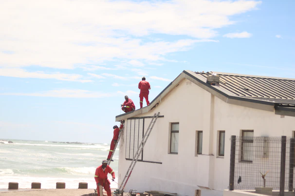 Workers in red suits on a white building roof